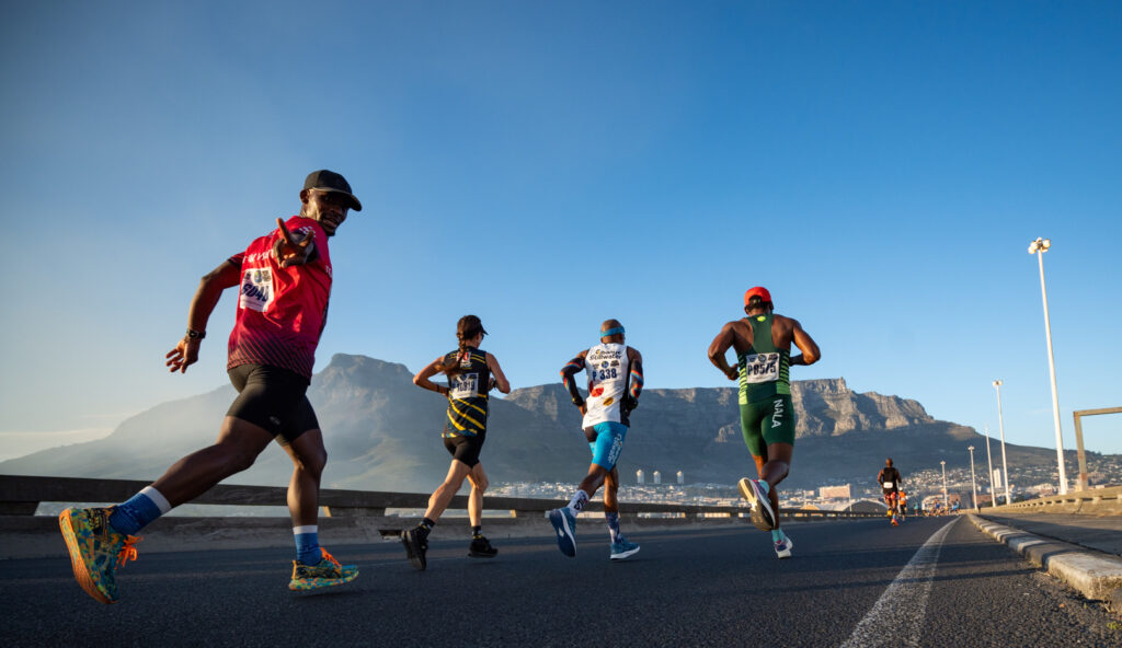 Men and women running on road in Cape Town with view of Table Mountain