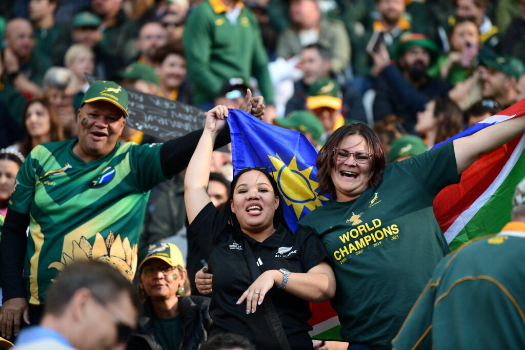 A Springbok and All Blacks supporter celebrate together during a rugby match at DHL Stadium in 2024